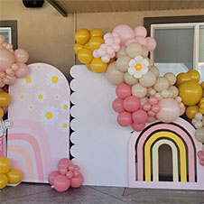 Colorful balloon arch and pastel backdrop with a rainbow design for an event.