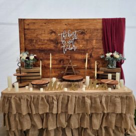 Rustic wedding decor with candles, "Mr & Mrs" signs, and a wooden backdrop.