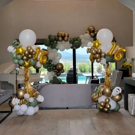 A stylish living room decorated with balloon arches featuring number "16" for a celebration.