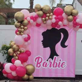 Backdrop with a Barbie silhouette and logo, framed by pink and gold balloons.