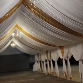 Elegant hall with white and gold drapery and crystal chandeliers, taken from a low angle.