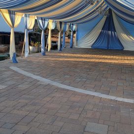 Elegant blue and white draped marquee tent over a brick patio area.