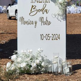 Wedding welcome sign with names Monica & Pedro and date 10-05-2024, adorned with white flowers.