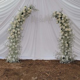 Floral wedding arch with "M&M" initials on draped white background.