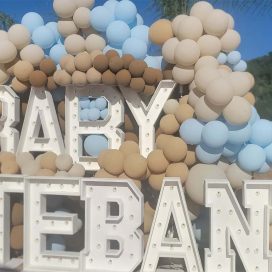 A balloon arch in blue and beige over large white letters spelling "BABY ESTEBAN".