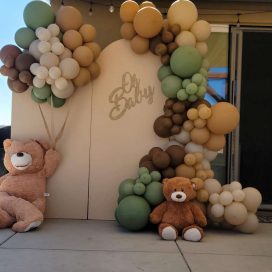 Party setup with balloon clusters and teddy bears, under a beige canopy with "Oh Baby" sign.